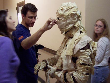 UIvsAM director Chris Lukeman adjusts the Mummy mask on an unidentified performer while actresses Andrea Gordon (left) and Jenni Kitchka (right) await their cues. (Courtesy Chris Lukeman/IFV)